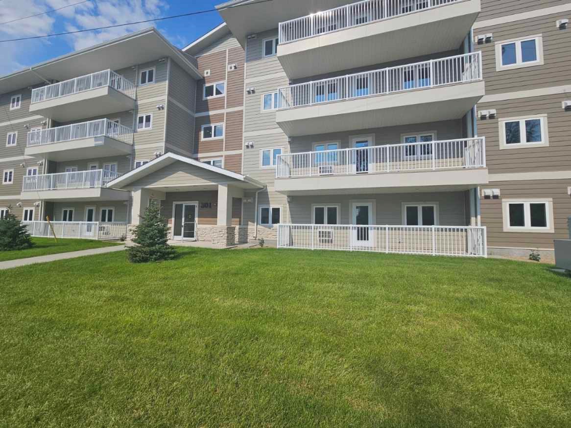 Killarney, Exterior Exterior of The Groves townhouseson Tracey Street in Brandon, Manitoba. The two-storey townhouses are painted in dark earth tones and light grey, with brick facing around the entrances. Parking is available directly in front of each unit.